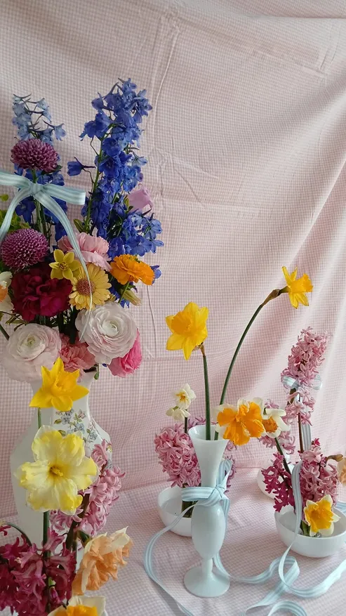 plusieurs petits bouquets de fleurs posés sur un fond de nappe de couleur rose à carreaux, comprenant des fleurs de couleur orange, rose, jaune, violet et vert