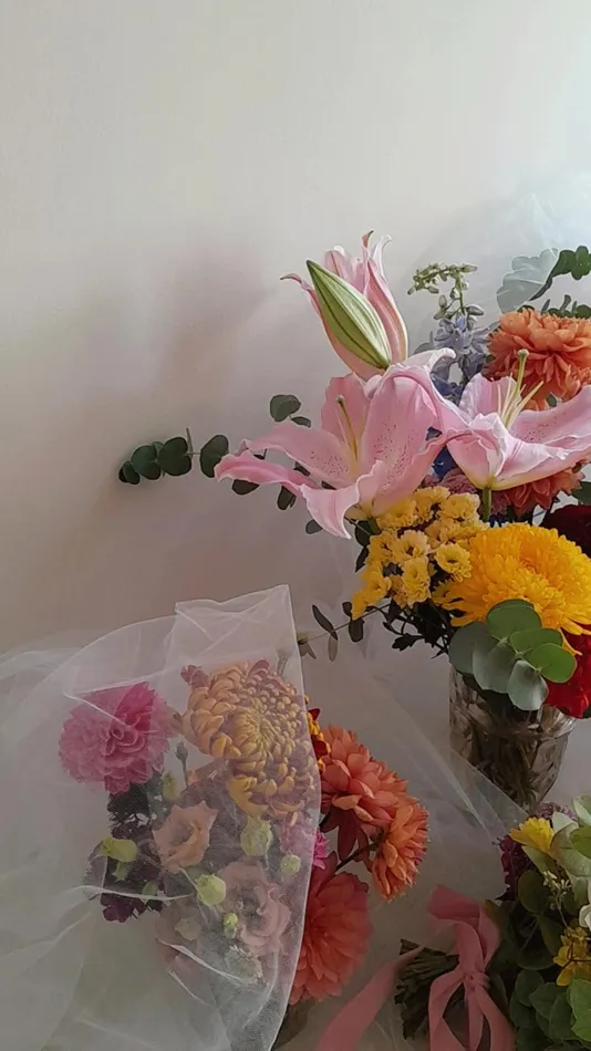 plusieurs bouquets de fleurs recouverts d’une nappe de voile blanc avec des fleurs composées des couleurs rose, jaune et orange