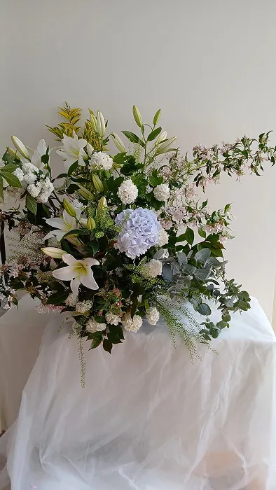 sur une table se trouve un gros bouquet de fleurs, rempli de fleurs blanches et de feuilles vertes