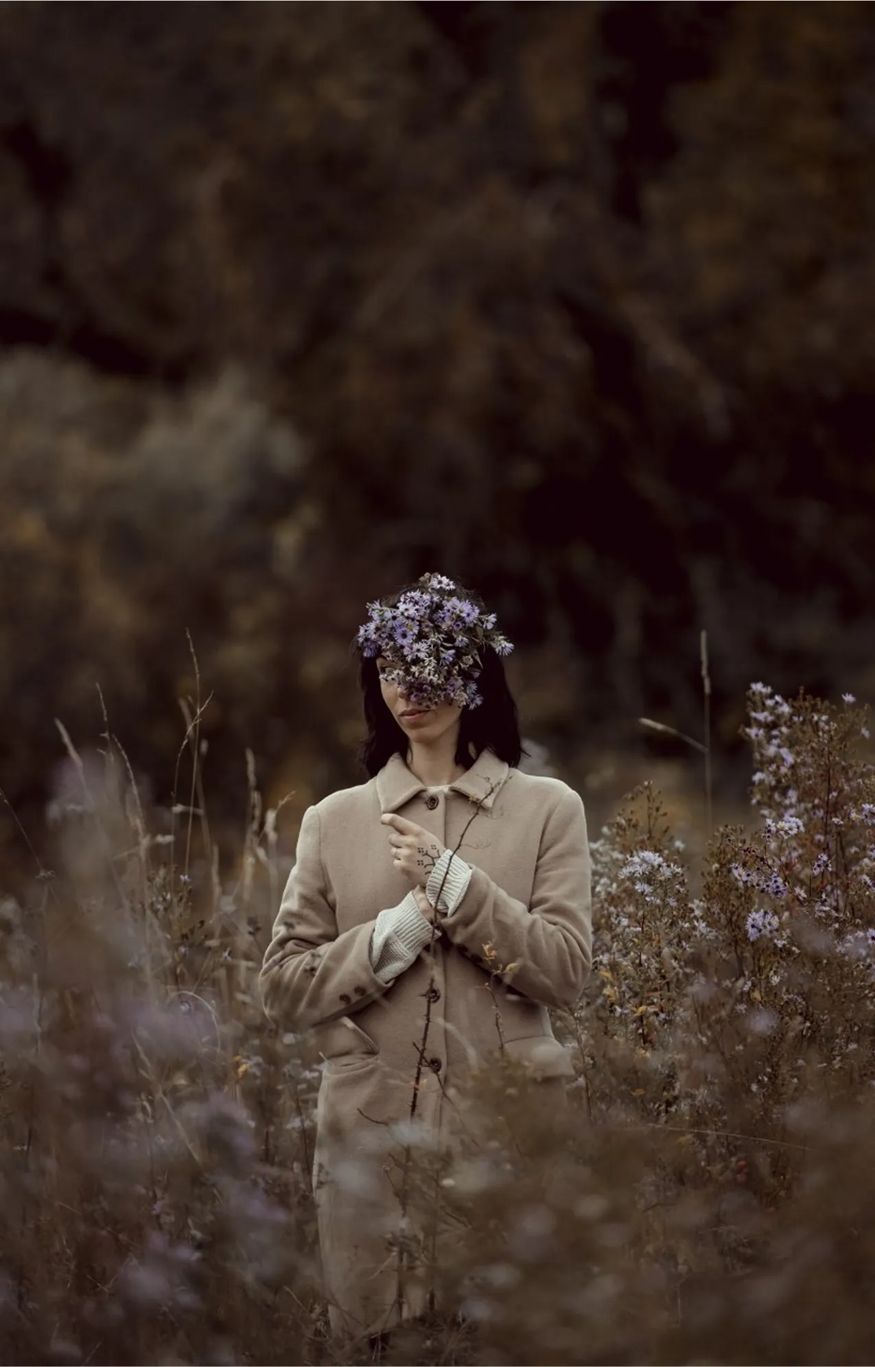 dans un champ se trouve une femme avec un bouquet de fleurs violettes sur le visage