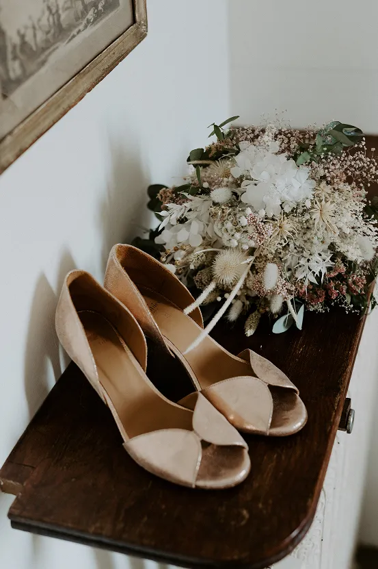 une photo épurée de ballerines de mariage avec un bouquet de fleurs blanc