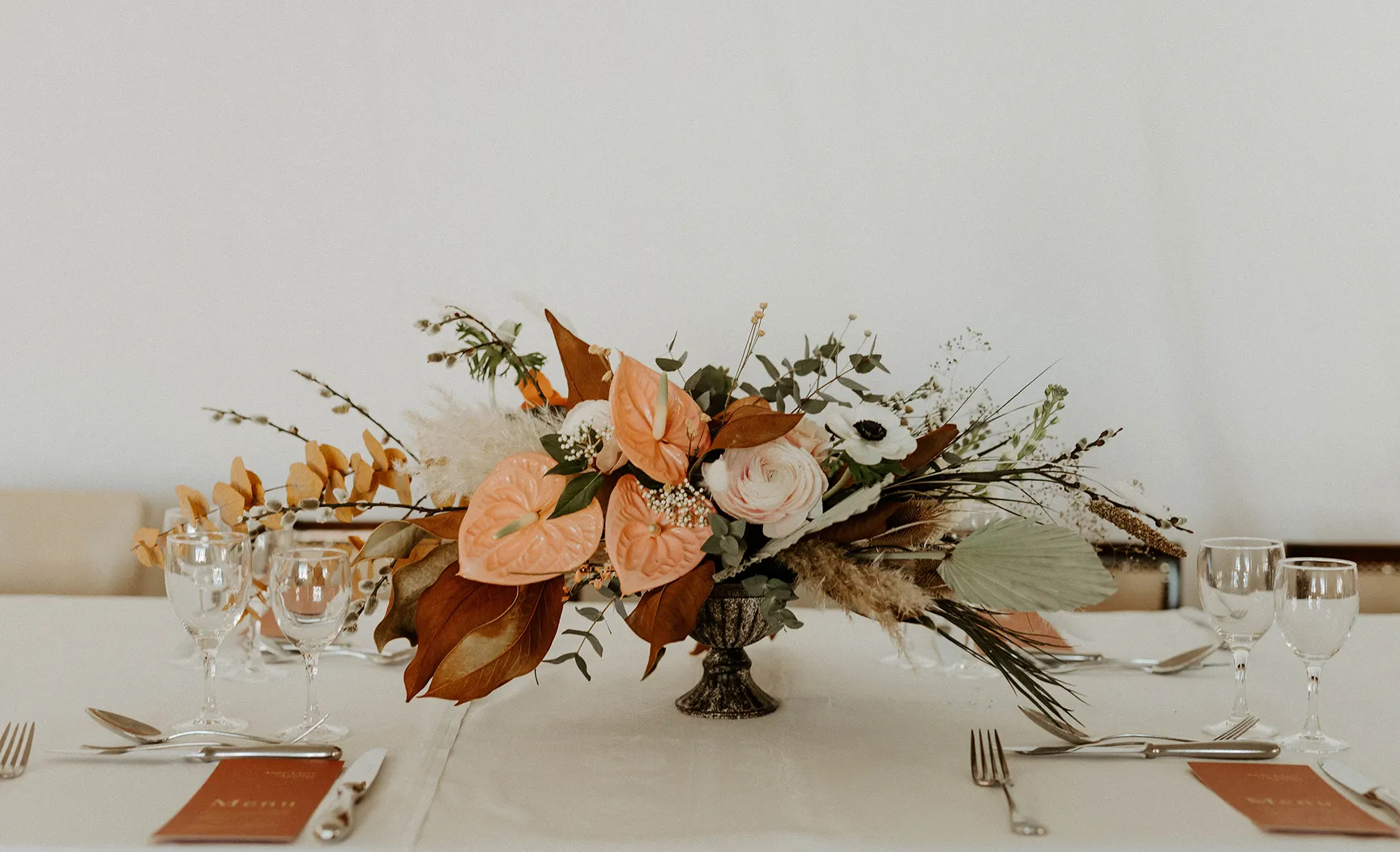sur une table dressée, recouverte d’une nappe blanche, se trouve un vase avec une composition florale, l’esthétique de fleurs rose pâle et rose très clair