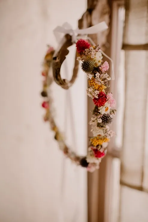 une composition de fleurs séchées disposées en anneau suspendu à un crochet