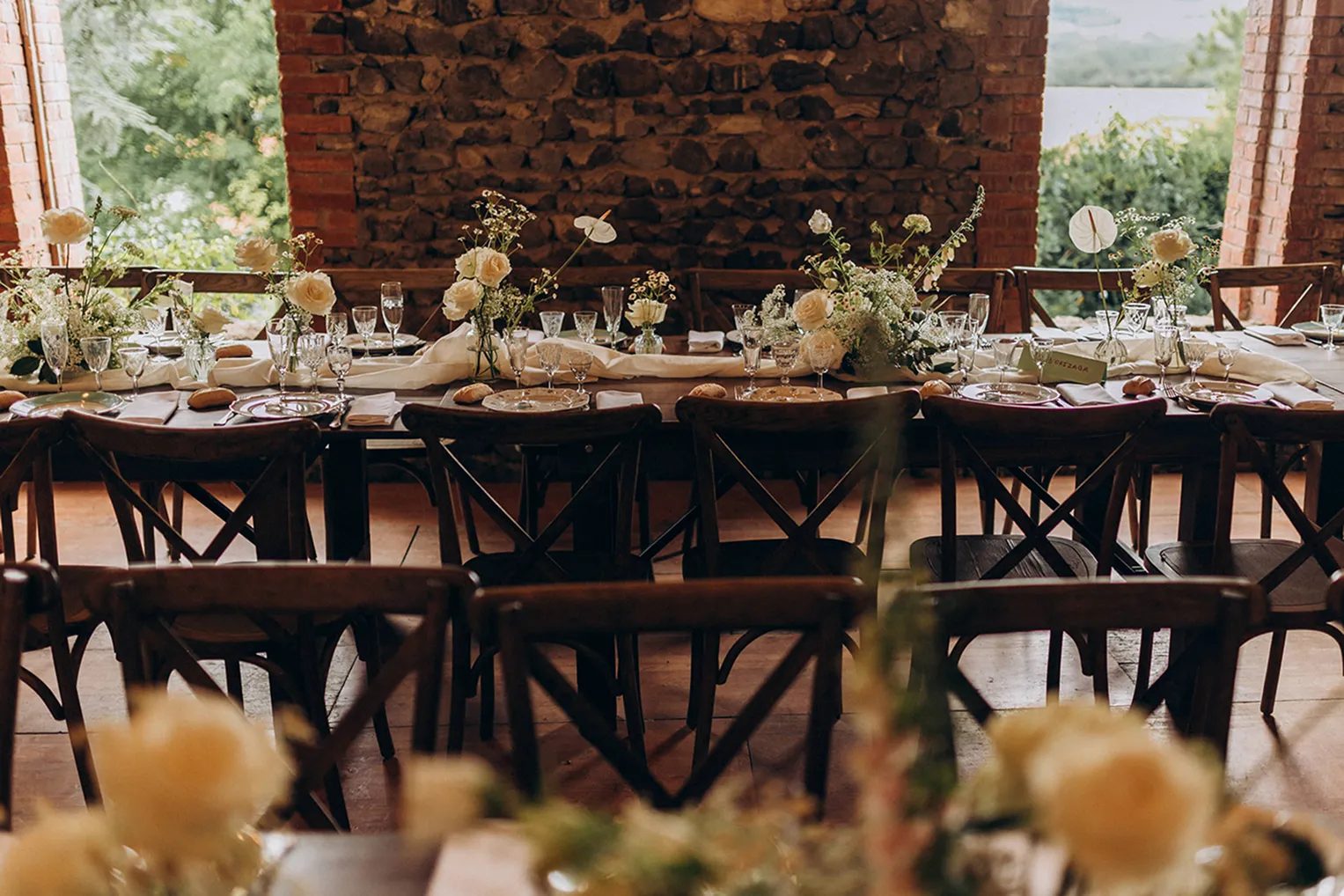 une table dressée avec des chaises en bois, ainsi que des fleurs lors d’une représentation d’un mariage
