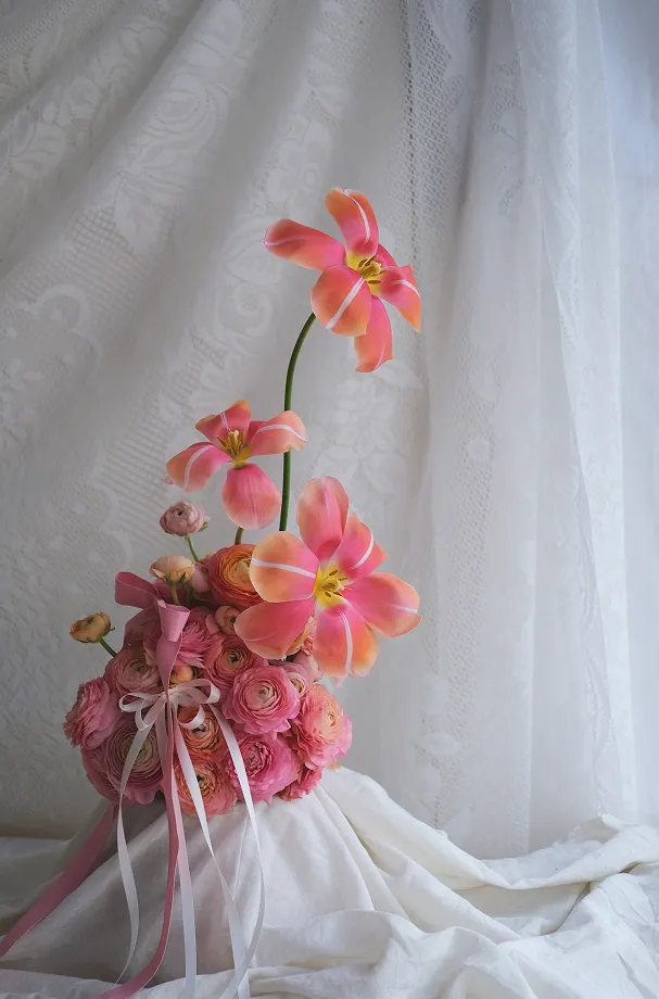 sur un support vêtu d’une nappe blanche se trouvent des fleurs roses de différentes tailles et formes