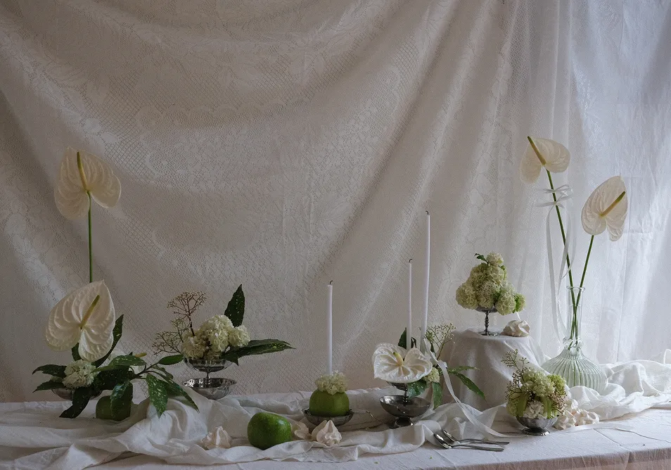 sur un fond blanc nappé se trouvent divers bouquets de fleurs blanches avec des feuilles vertes
