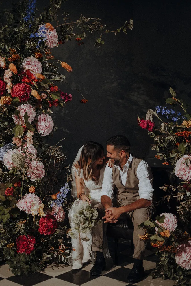 un couple de mariés entouré d’une composition florale de diverses couleurs