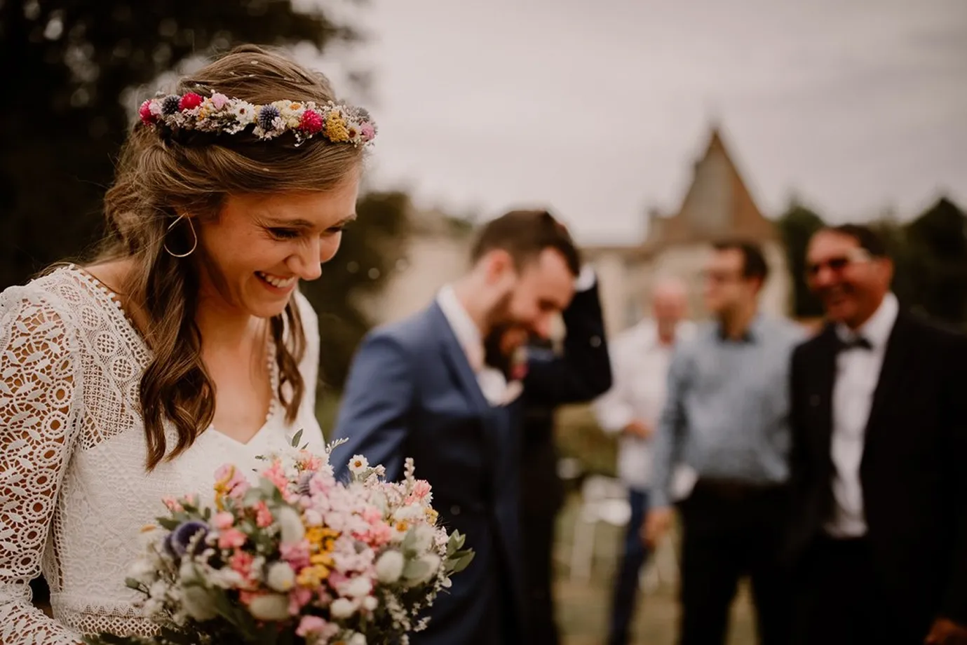 une femme mariée tenant dans ses mains un bouquet de fleurs avec un grand sourire et un serre-tête de fleurs