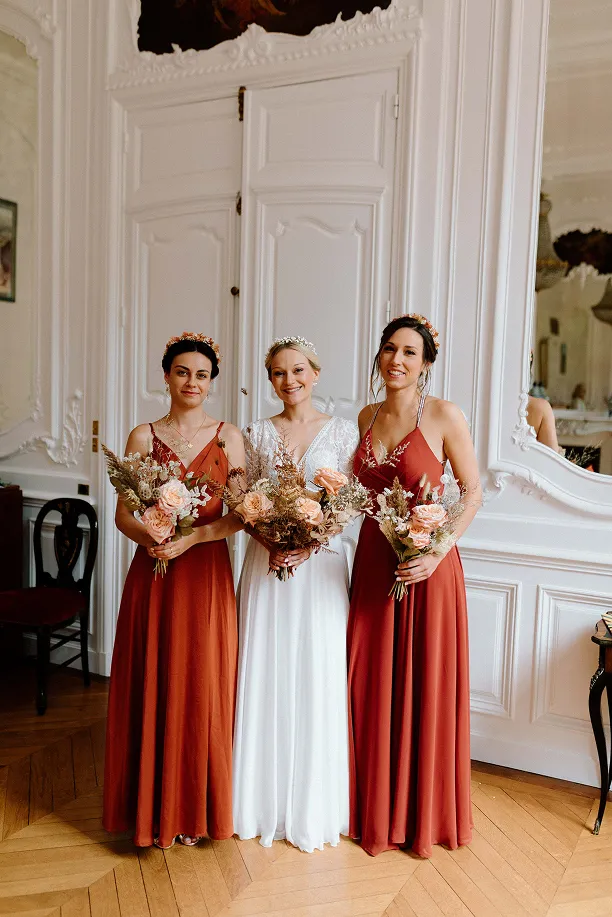 lors d’un mariage, trois femmes dont la mariée au milieu tiennent chacune dans leur main un bouquet de fleurs
