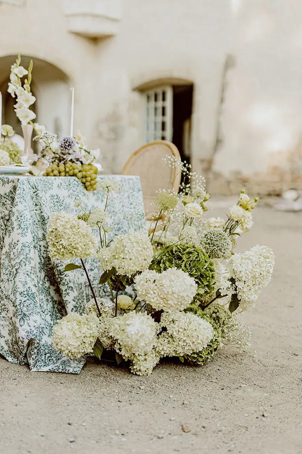une photo artistique d’une table lors d’un mariage avec des fleurs blanches et vertes