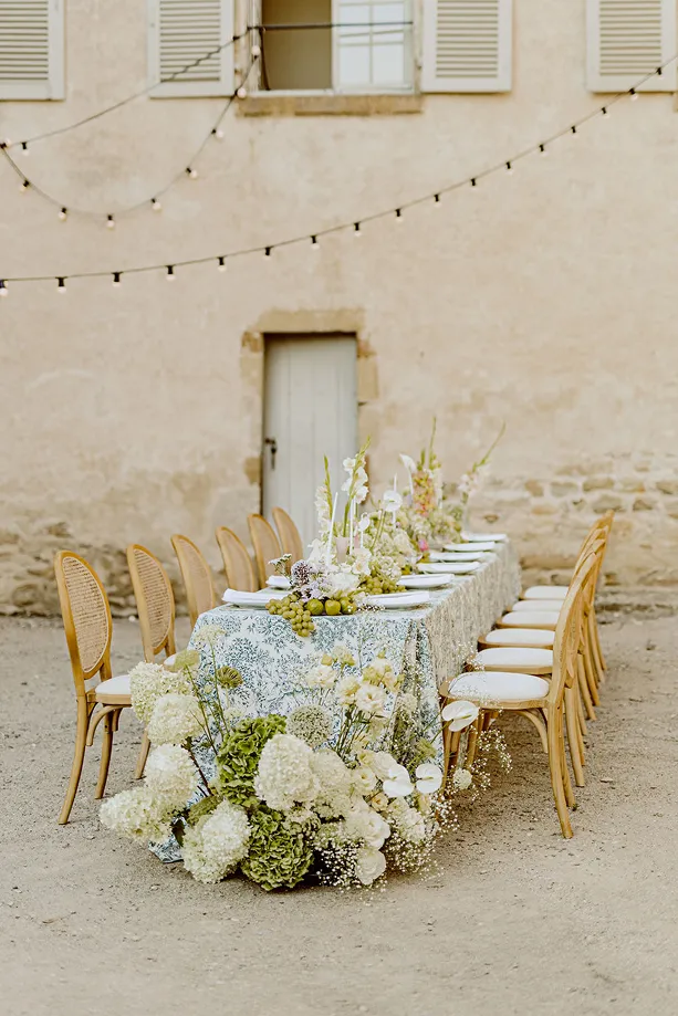 une photo de l’intégralité d’une table de mariage avec des fleurs blanches et vertes et du raisin